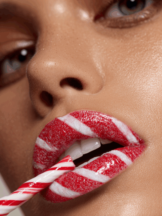 Bold holiday makeup with candy cane striped lips, festive Christmas beauty design for 2025.