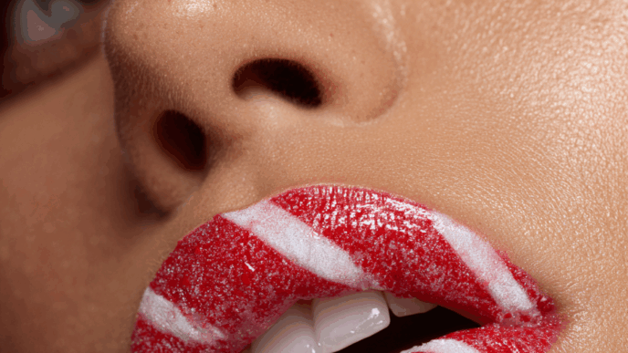 Bold holiday makeup with candy cane striped lips, festive Christmas beauty design for 2025.