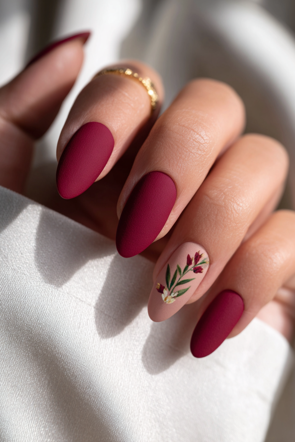 Rich maroon almond nails finished with a soft, velvety matte topcoat for a luxurious warm winter texture.