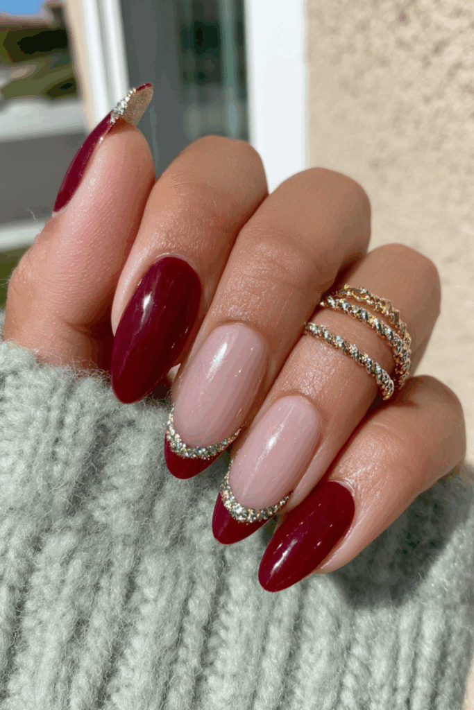 Almond nails with a deep berry red French V-tip design outlined with a thin border of silver rhinestones.