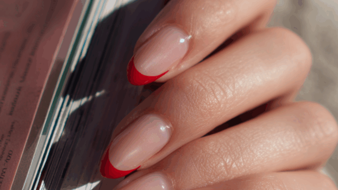 Almond-shaped nails with glossy red French tips topped with a shimmery chrome glaze, a trendy high-shine manicure design.