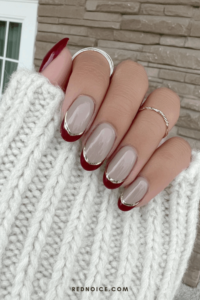 Almond-shaped nails with a matte nude base and glossy red French tips, creating a striking contrast in texture for a modern manicure.